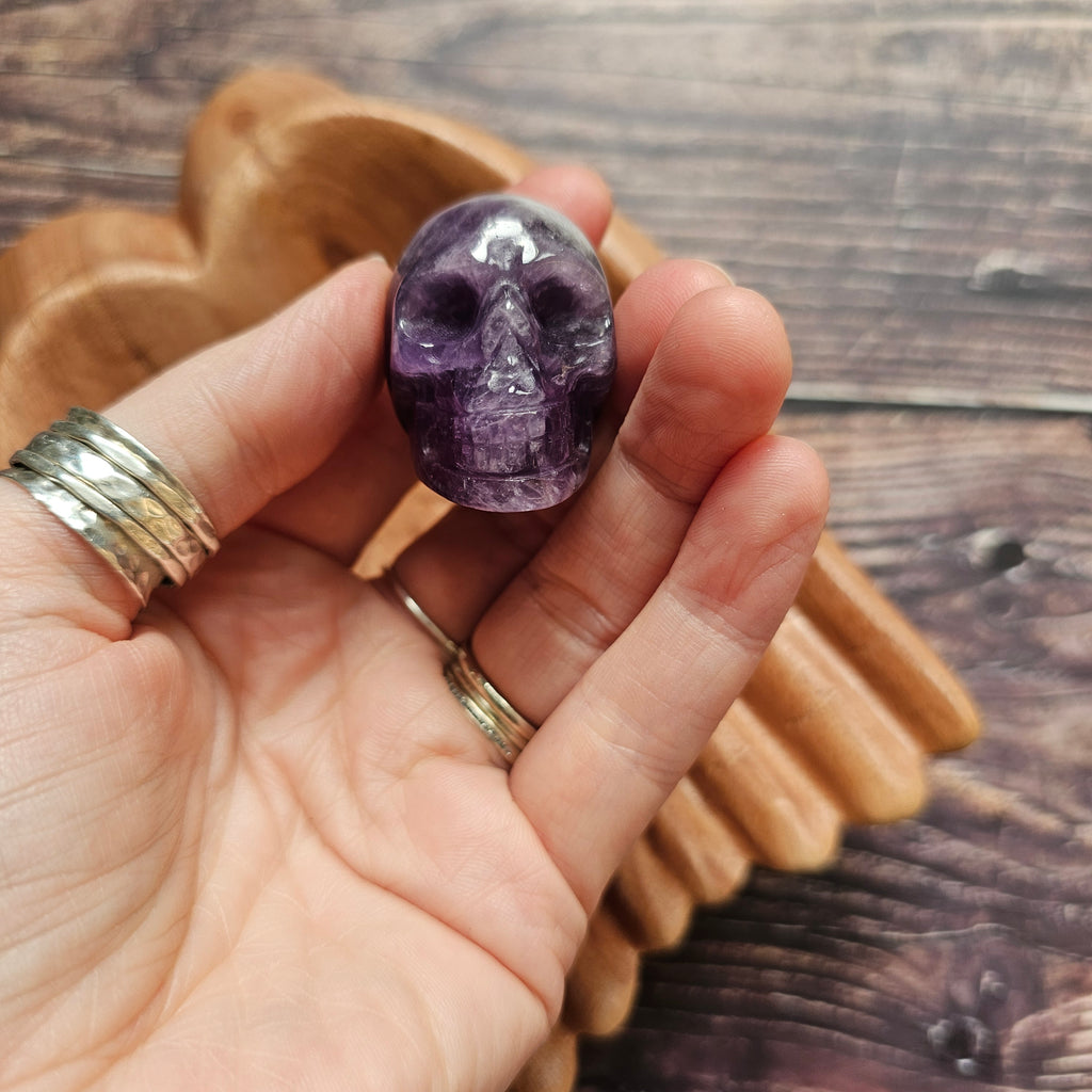 A carved Amethyst crystal skull held in a hand