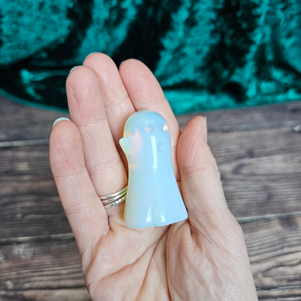 The back of an Opalite carved crystal ghost held in a person's hand