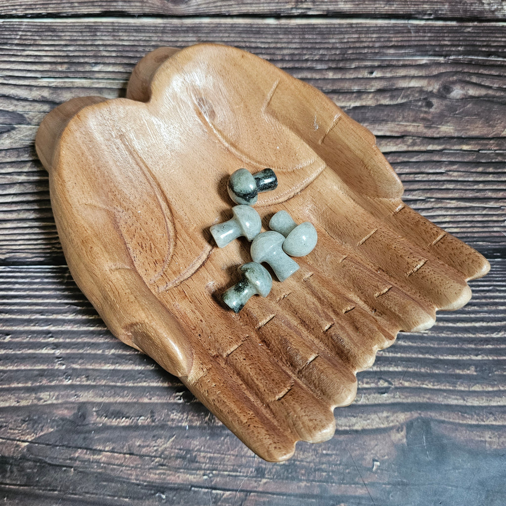 Five miniature crystal mushrooms placed on a wooden surface.