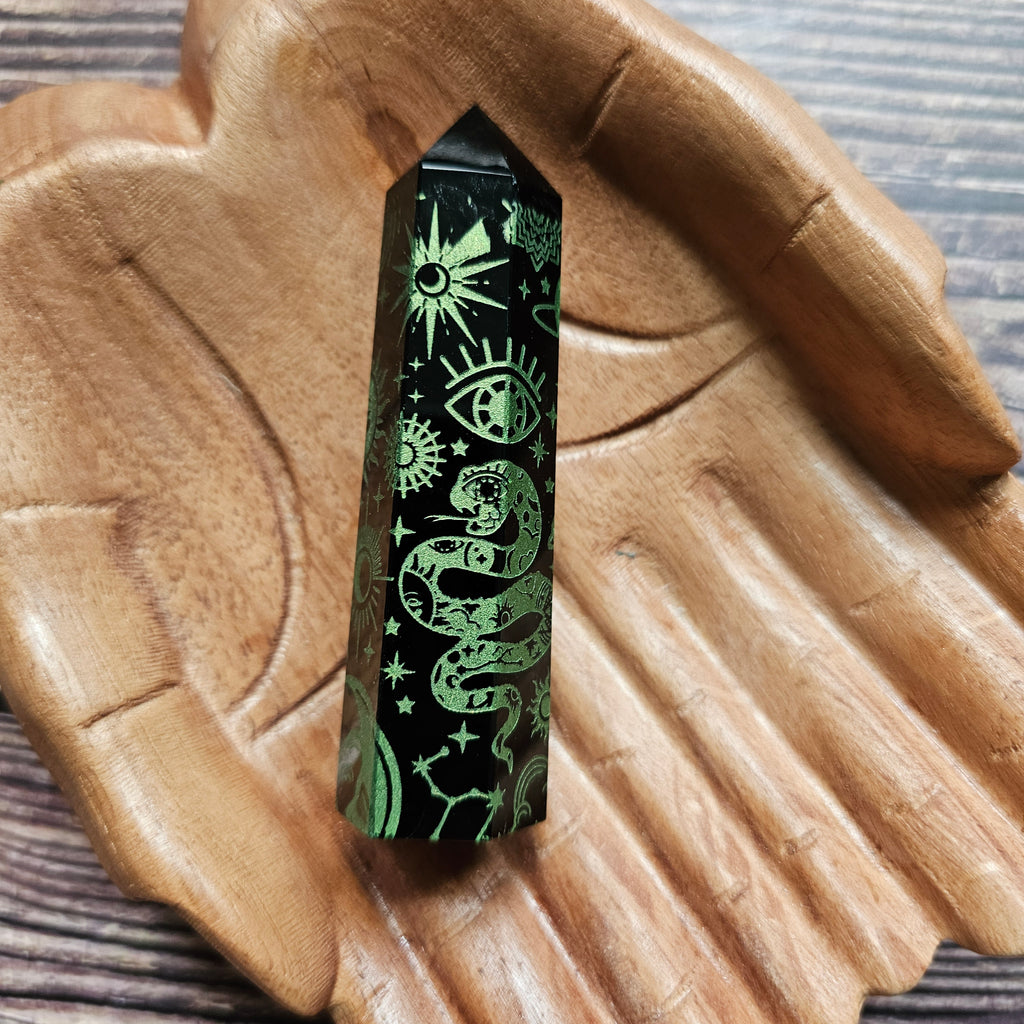 A Black Obsidian Generator with celestial designs displayed on a wooden hand-shaped tray.