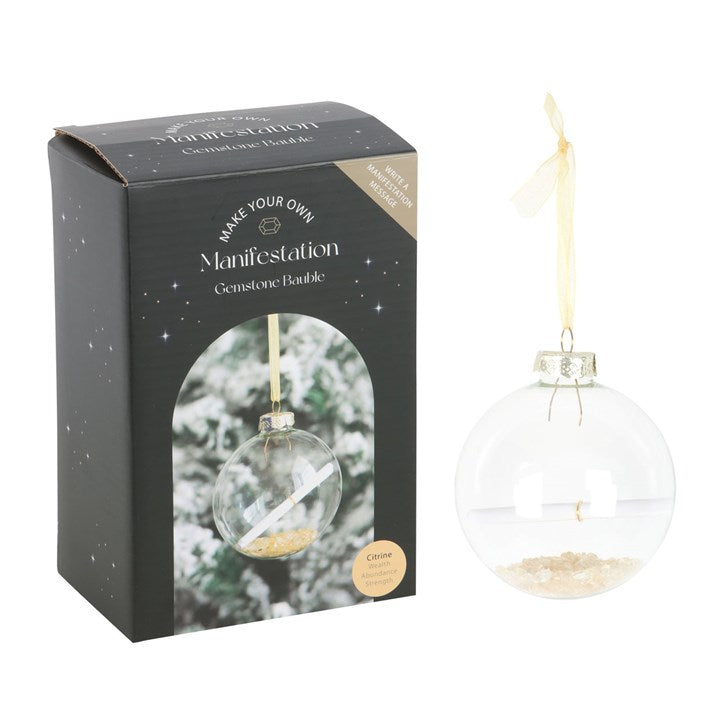 A glass bauble on a gold string with a scroll of paper inside along with crystals and its box.