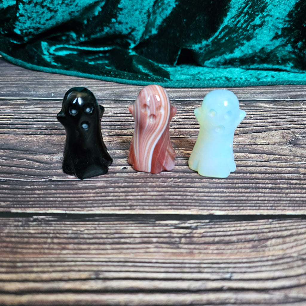 Three carved crystal ghosts on a wooden background