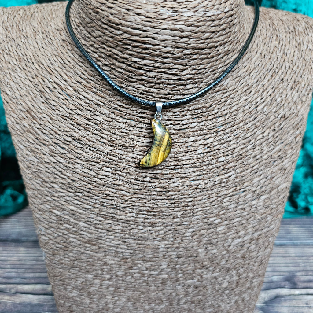 A crescent moon shaped crystal pendant on a black cord displayed on a mannequin 