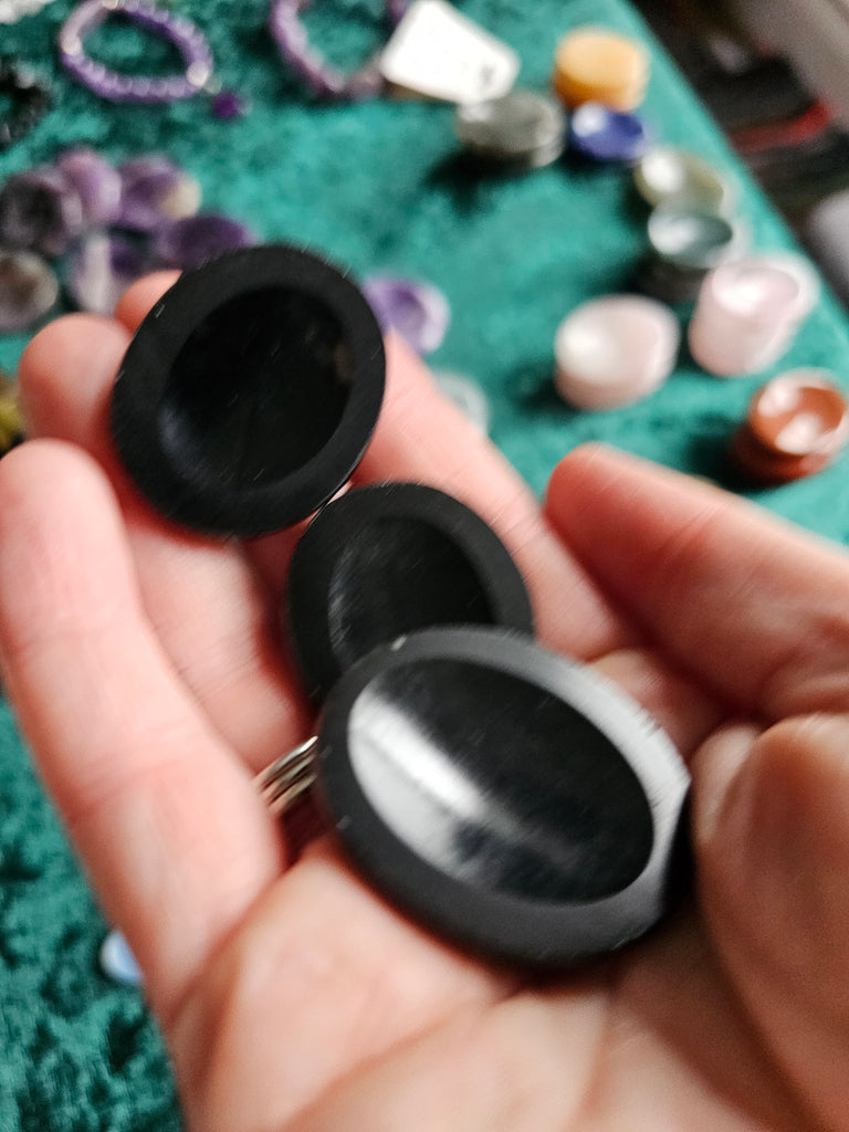 Three black polished crystal thumbstones being held in a hand