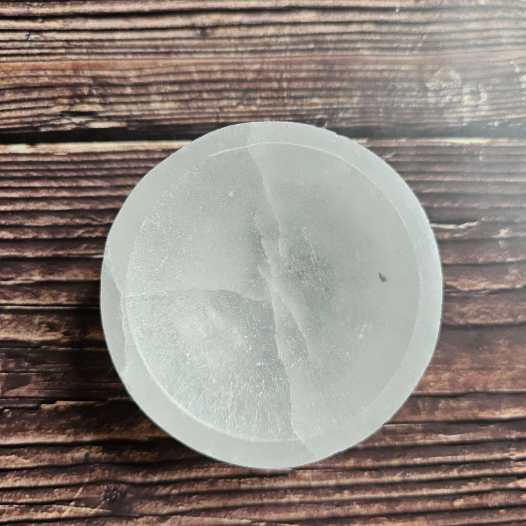 A white selenite bowl on a wooden surface