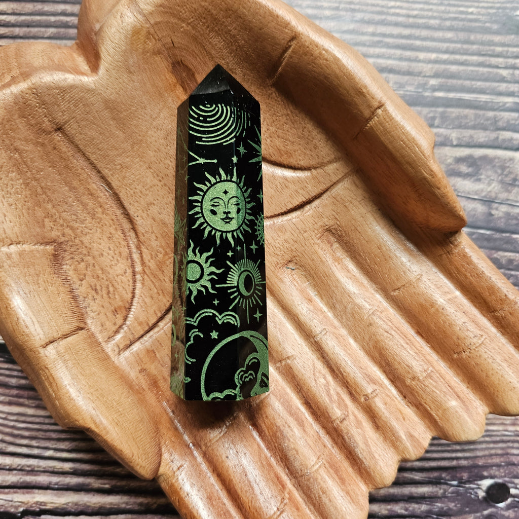A Black Obsidian Generator with celestial designs displayed on a wooden hand-shaped tray.