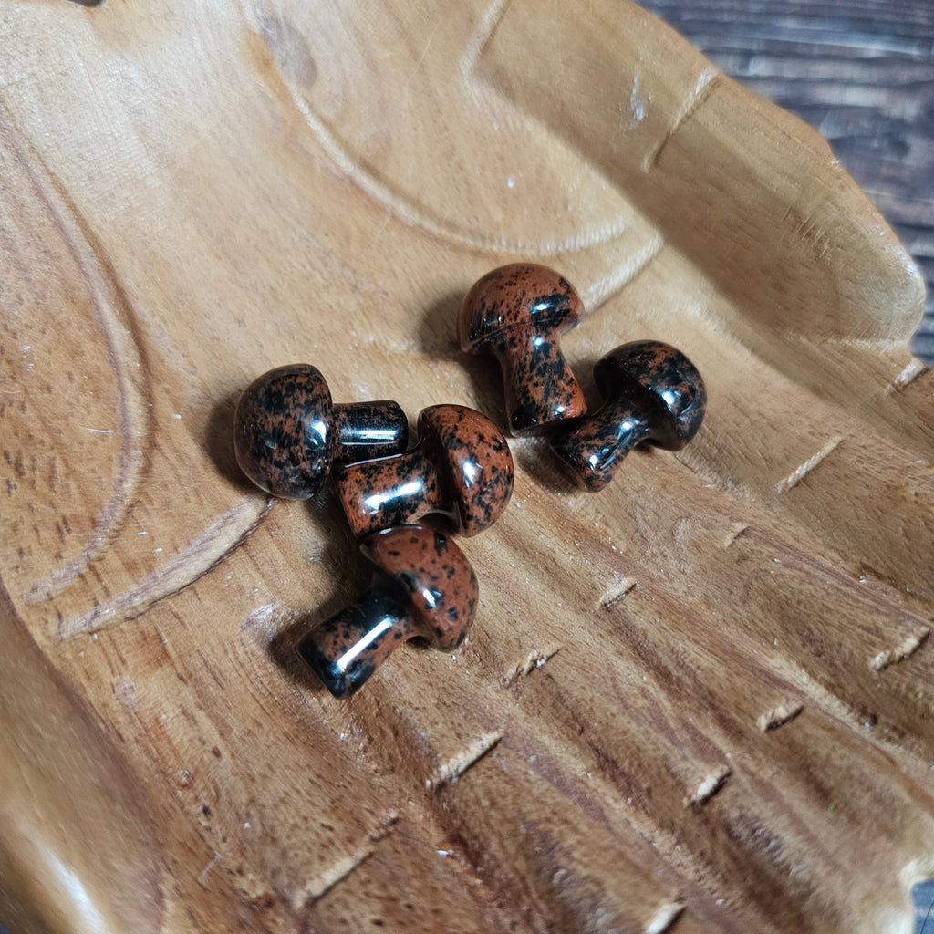 Five miniature crystal mushrooms placed on a wooden surface.
