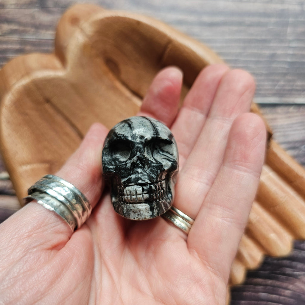 A carved crystal black and grey skull held in a hand
