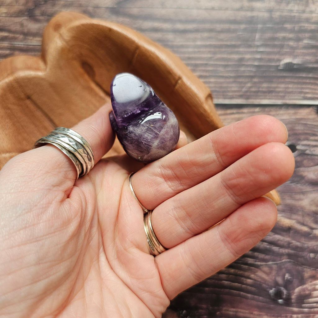 A carved Amethyst crystal skull held in a hand to show underneath 