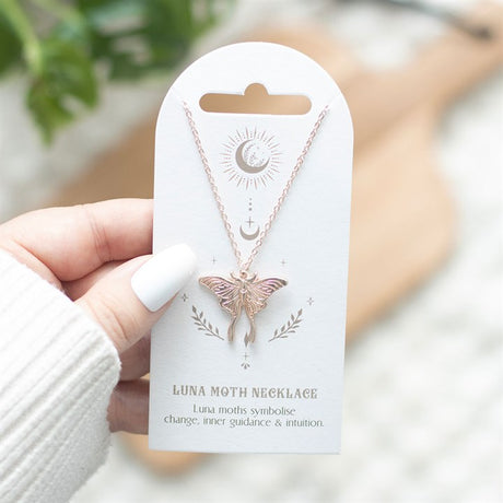 A light luna moth necklace with a dangling pendant, displayed on a card with the text 'LUNA MOTH NECKLACE' and a description of the luna moth symbolism.