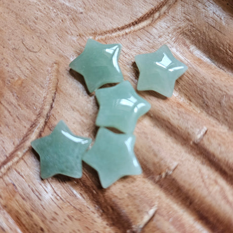 A collection of green aventurine mini stars arranged on a wooden surface.
