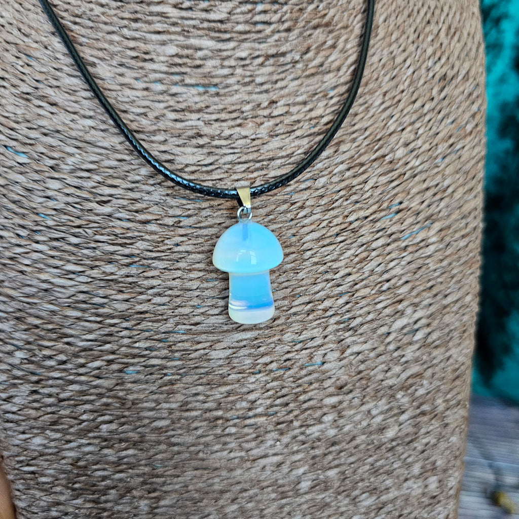 A mushroom-shaped crystal pendant attached to black cord, displayed on a mannequin. 