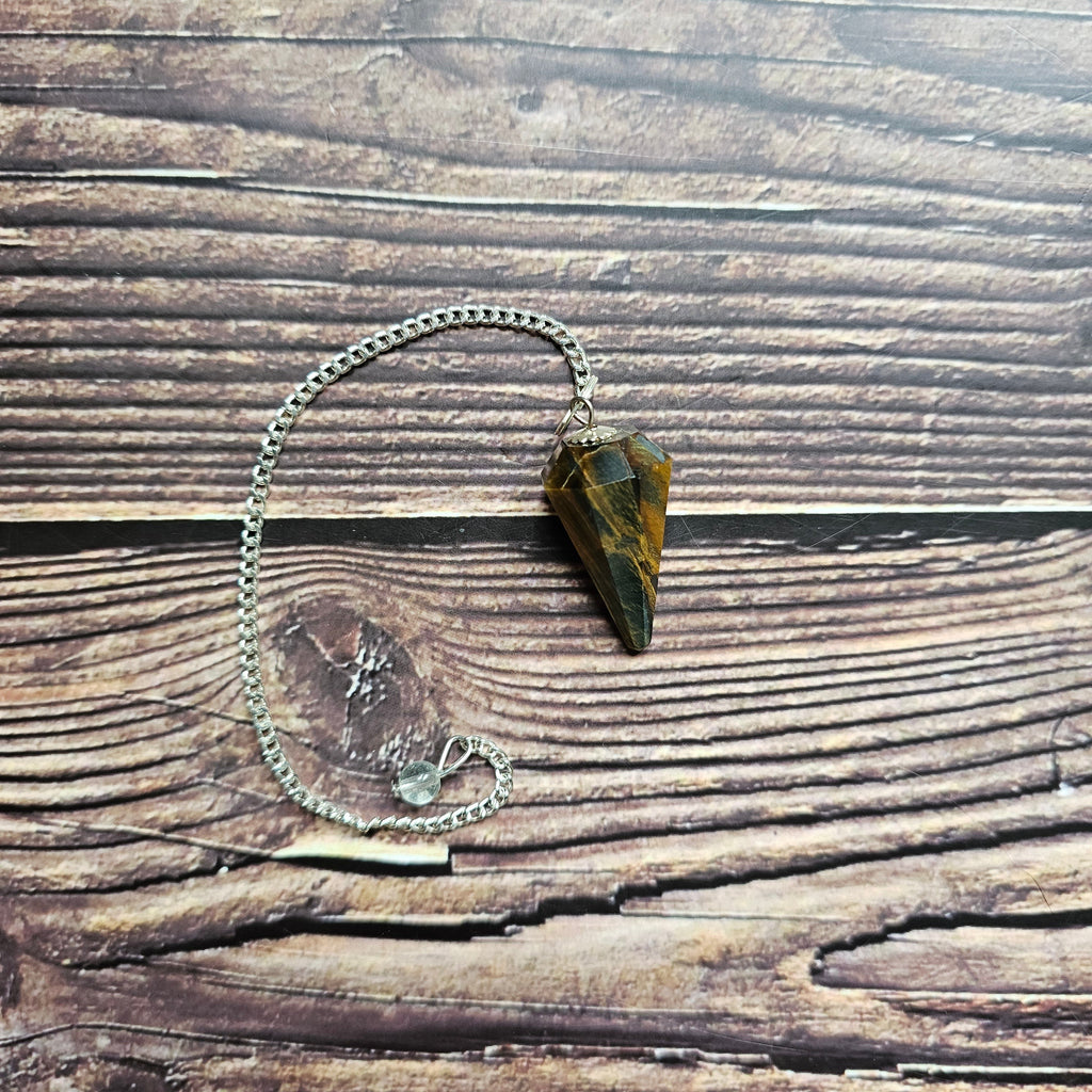 A Tiger's Eye pendulum, displayed on a wooden surface.