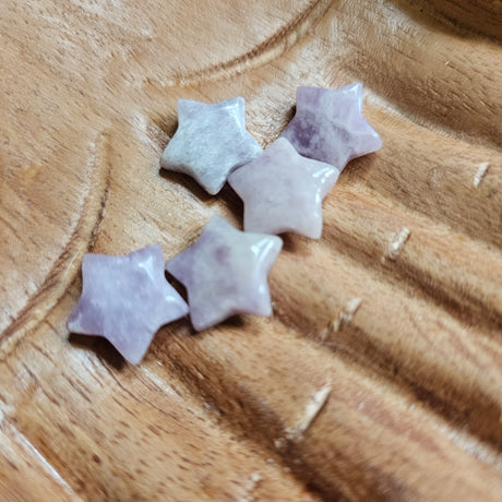 A collection of mini star-shaped Lepidolite stones, placed on a wooden surface.