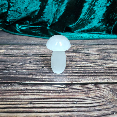 A selenite crystal mushroom stands on a wooden surface. 