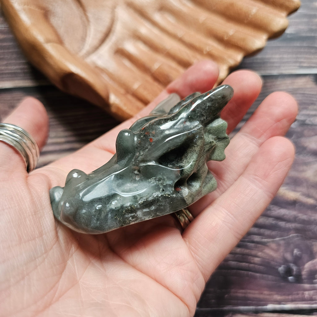 A green crystal dragon skull figurine, held in a hand