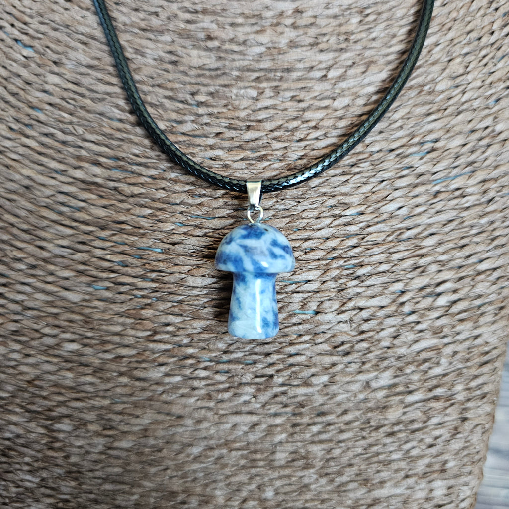 A mushroom-shaped crystal pendant attached to black cord, displayed on a mannequin. 