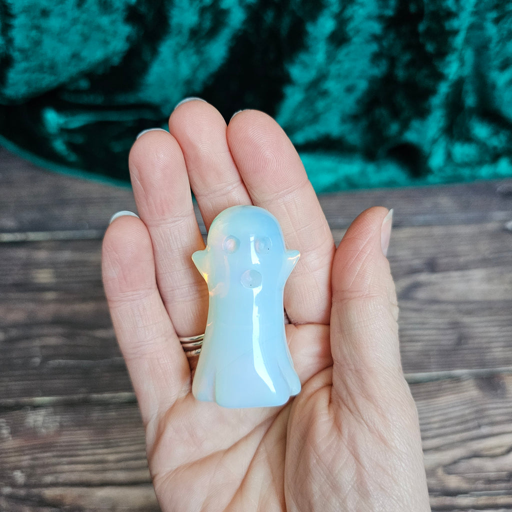 An Opalite carved crystal ghost held in a person's hand