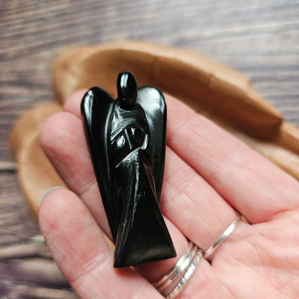 A carved crystal angel figurine held in a hand
