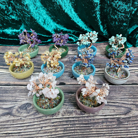 A collection of ceramic tea bowls with a crystal tree decoration on a wooden surface, with colours including green, blue, and purple.