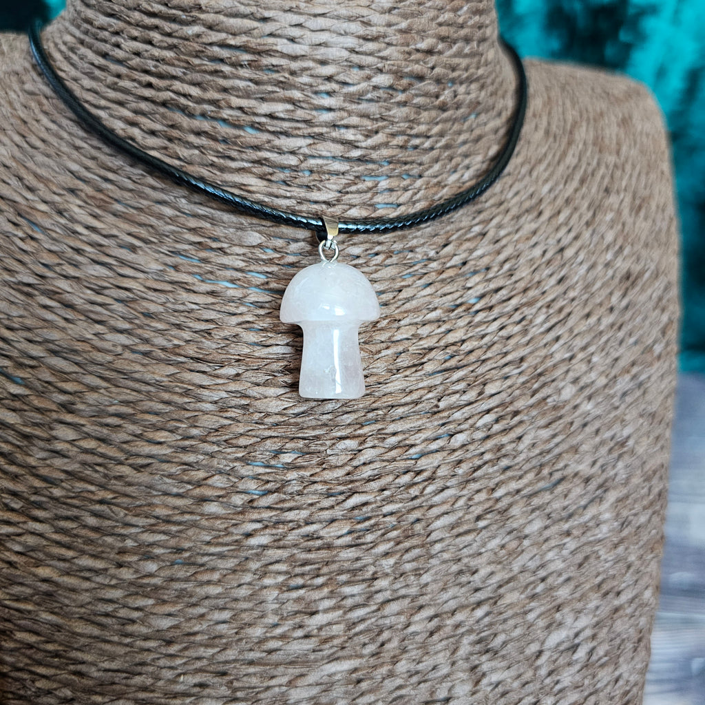 A mushroom-shaped crystal pendant attached to black cords, displayed on a mannequin. 