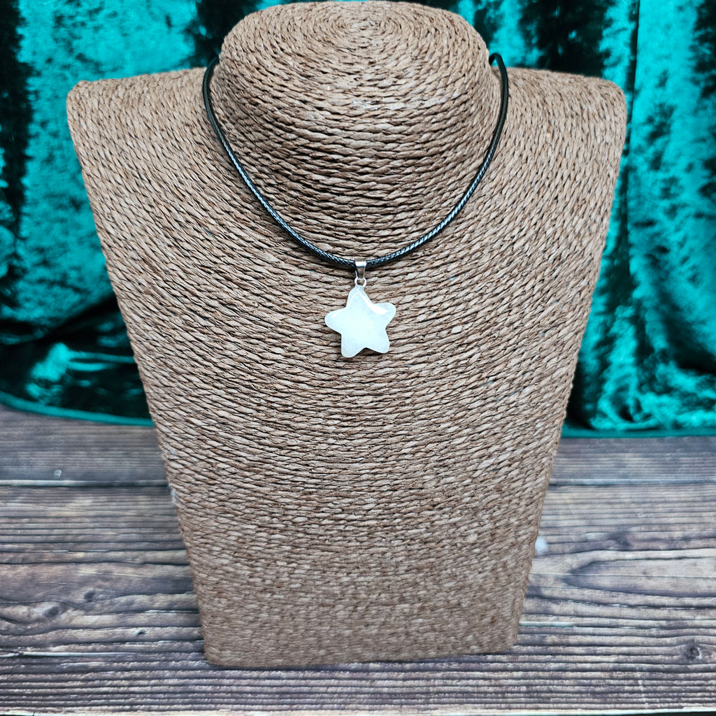 A star-shaped crystal pendant displayed on a brown mannequin, with a black cord.
