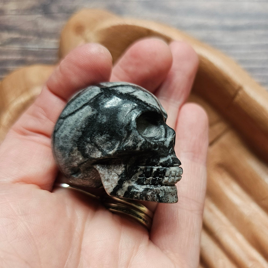 A carved crystal black and grey skull held in a hand