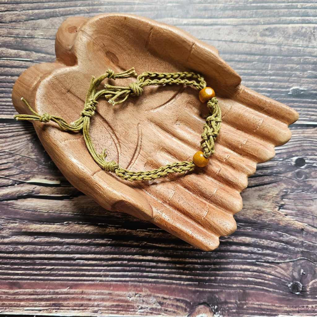 A sand-coloured crystal cord bracelet laid on a pair of wooden hands