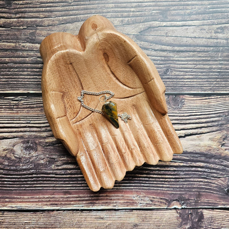 A Tiger's Eye pendulum, displayed on a wooden surface.