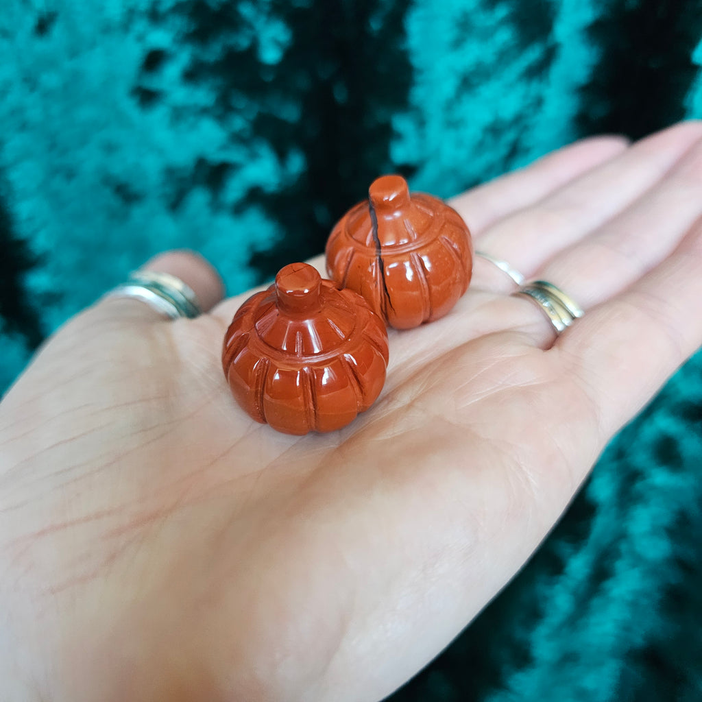 Two Red Jasper crystal pumpkins being held in someone's hand