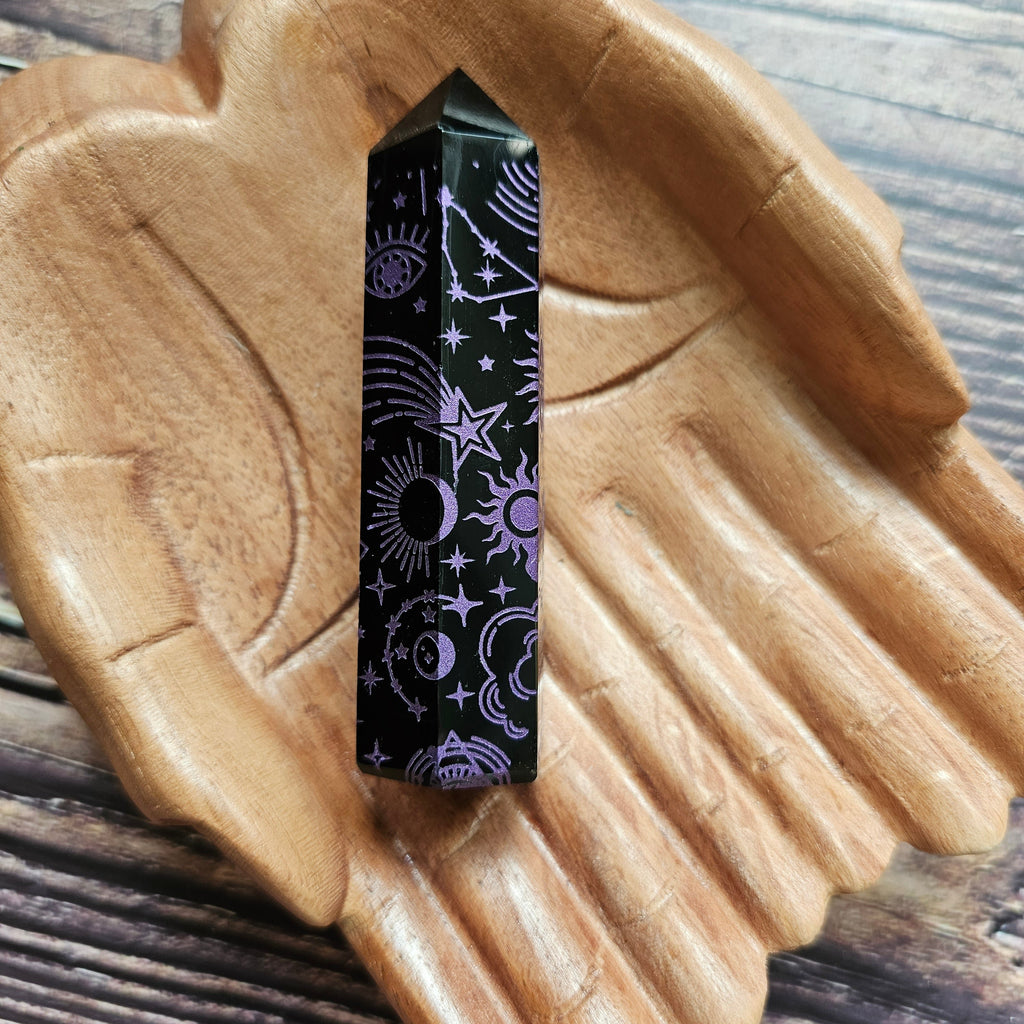 A Black Obsidian Generator with celestial designs displayed on a wooden hand-shaped tray.