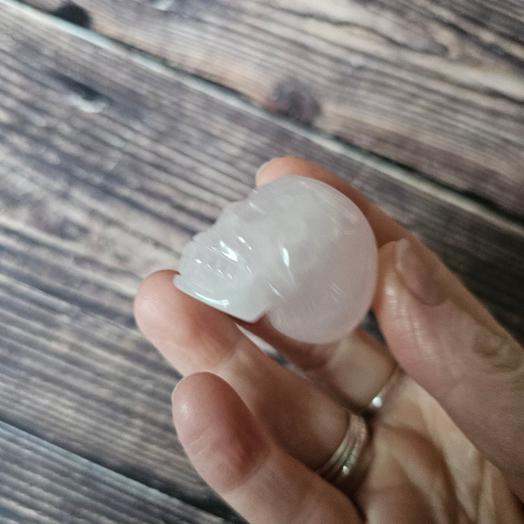 A carved pink crystal skull held in a hand