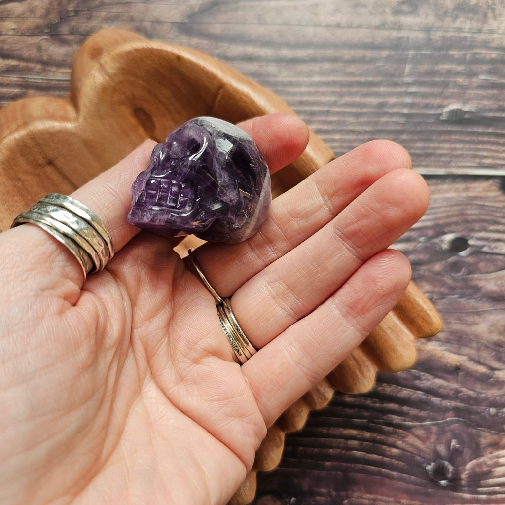 A carved Amethyst crystal skull held in a hand