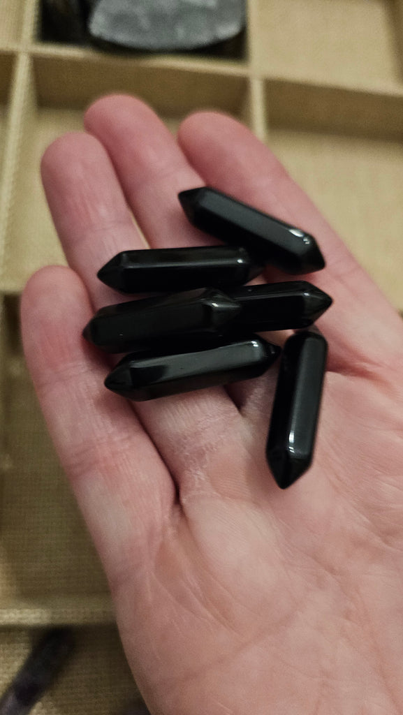 Small black double pointed crystals held in a hand