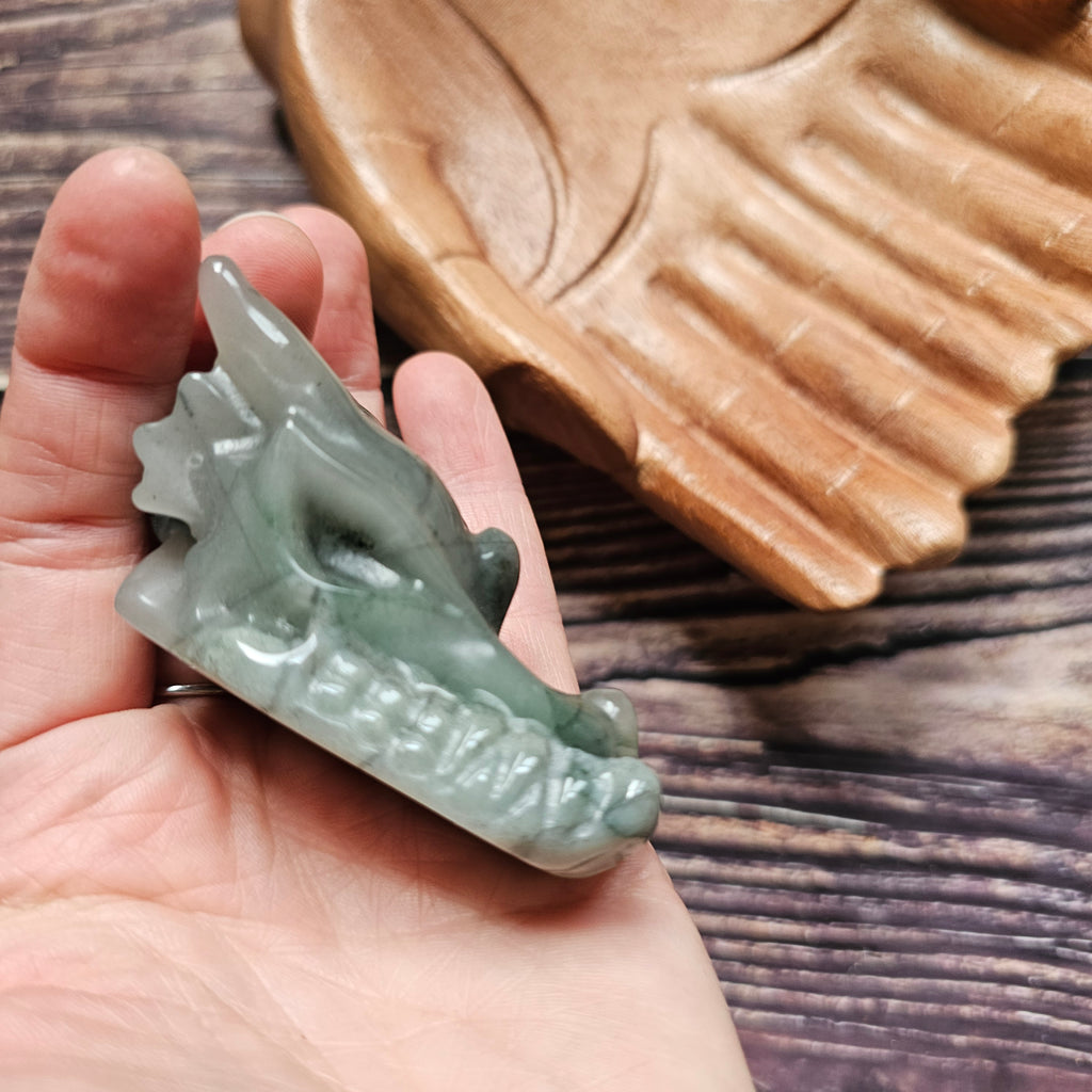A green crystal dragon skull figurine, held in a hand