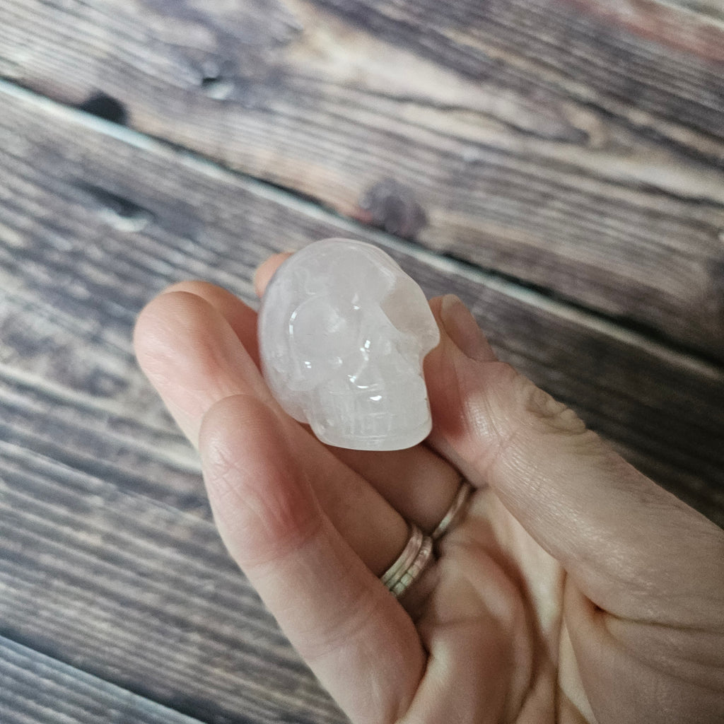 A carved pink crystal skull held in a hand
