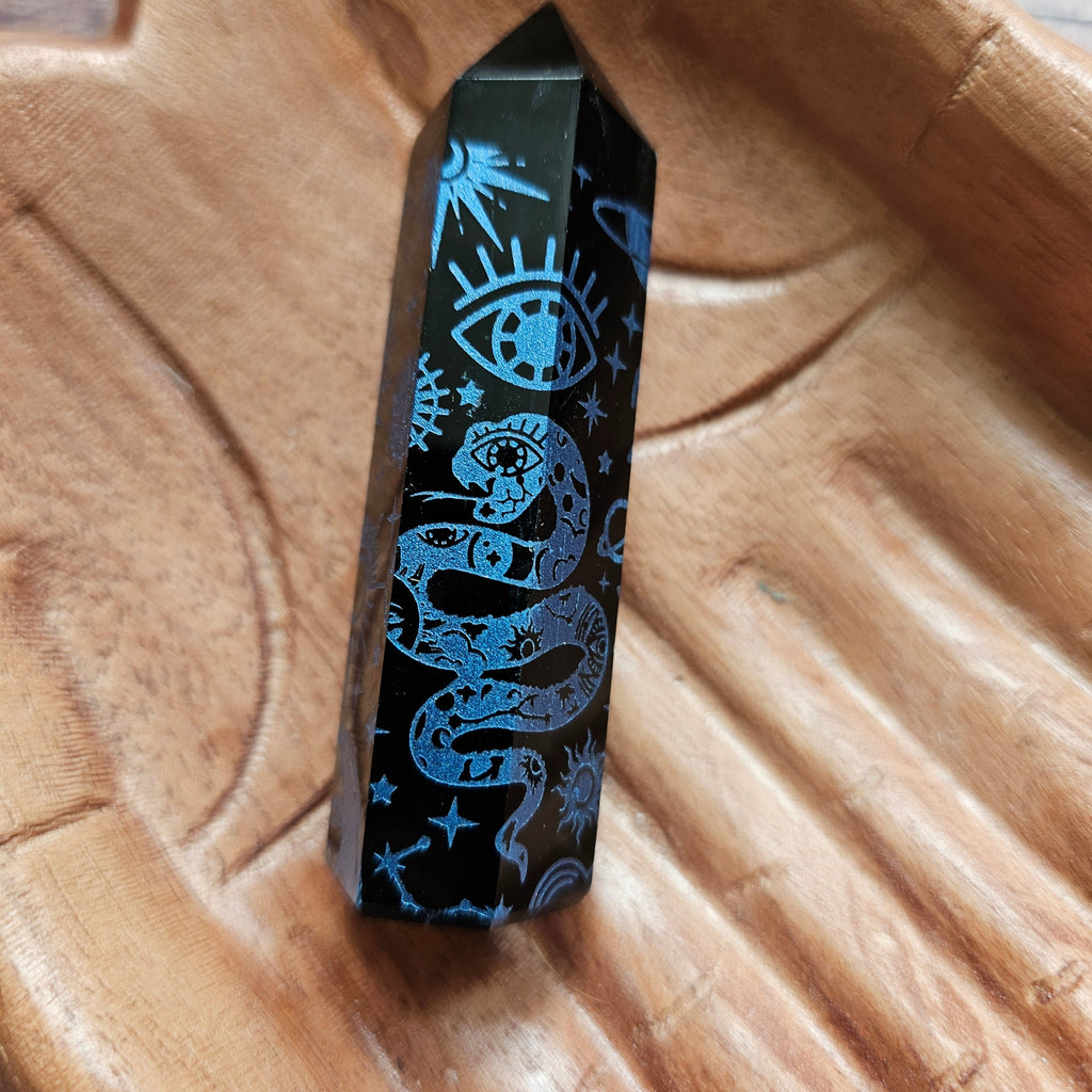 A Black Obsidian Generator with celestial designs displayed on a wooden hand-shaped tray.