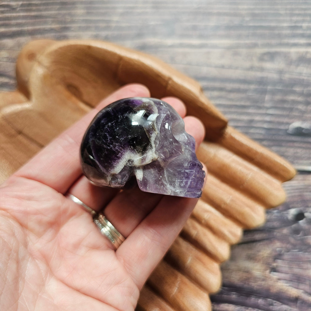 A carved Amethyst crystal skull held to the side in a hand