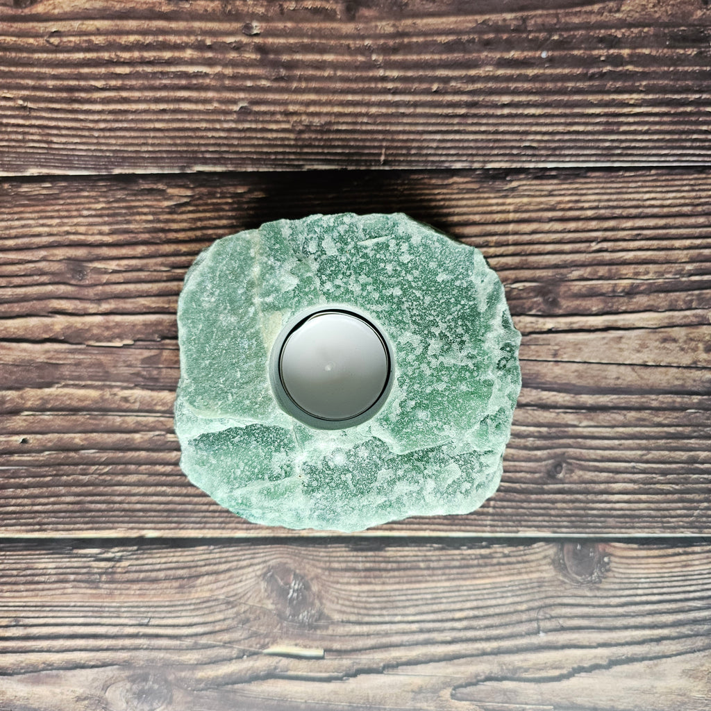A chunky rough, green aventurine stone tealight holder placed on a wooden surface.