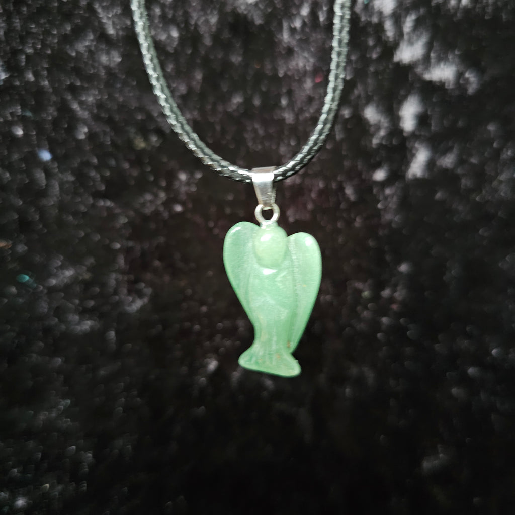 An angel-shaped crystal pendant attached to black cord necklaces on a dark background