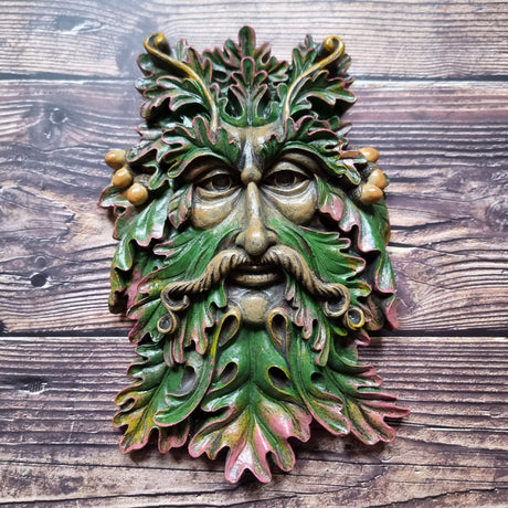 A green man plaque placed against a wooden background