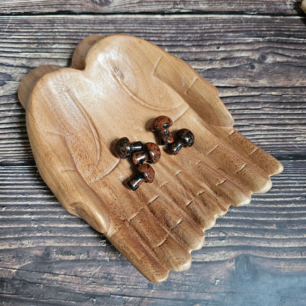 Five miniature crystal mushrooms placed on a wooden surface.
