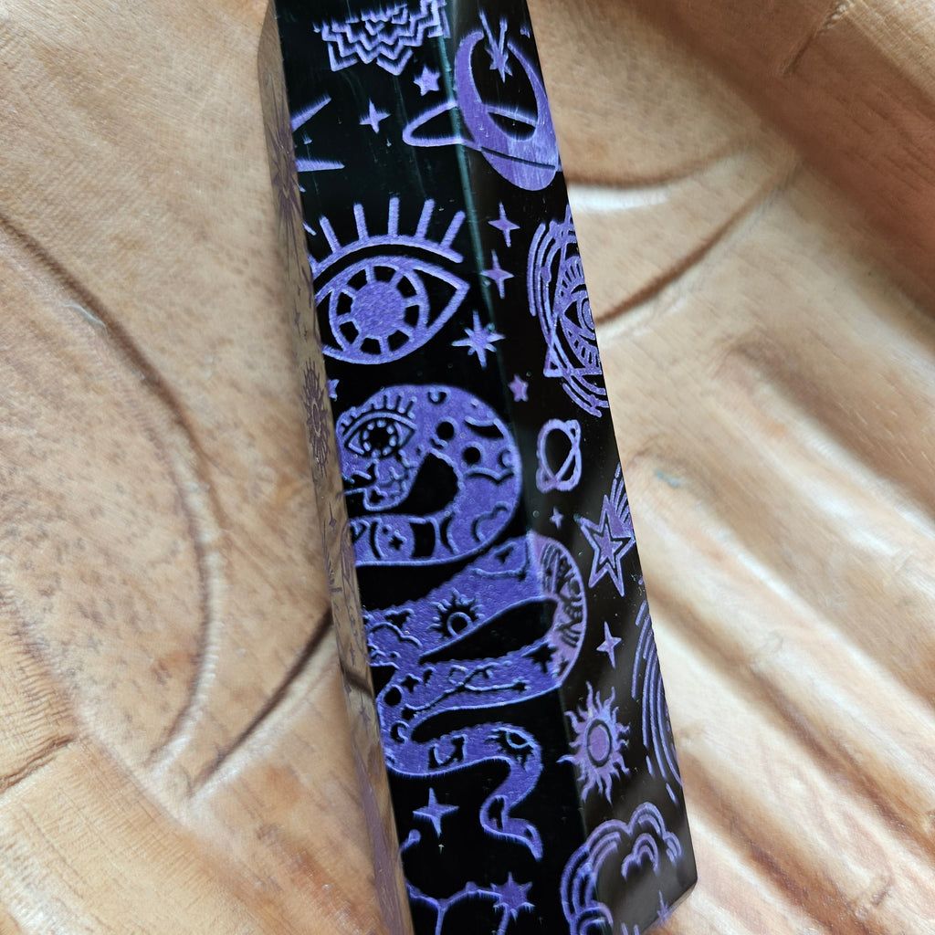 A Black Obsidian Generator with celestial designs displayed on a wooden hand-shaped tray.