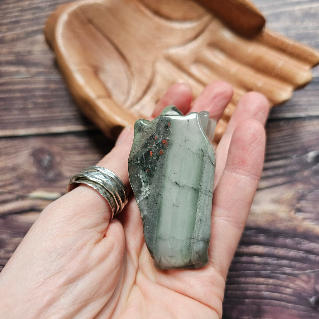 A green crystal dragon skull figurine, held in a hand