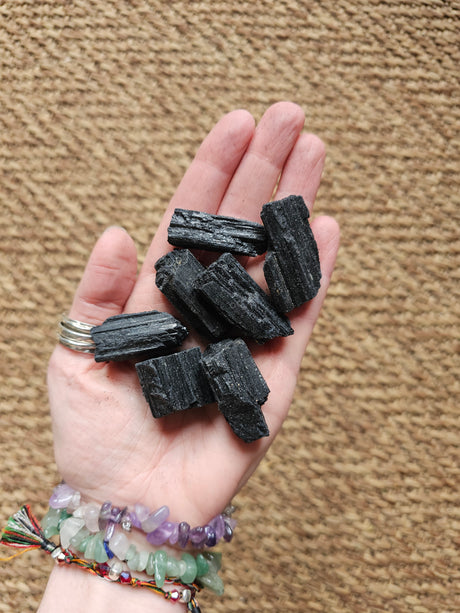 Hand holding black crystals against a beige carpet background