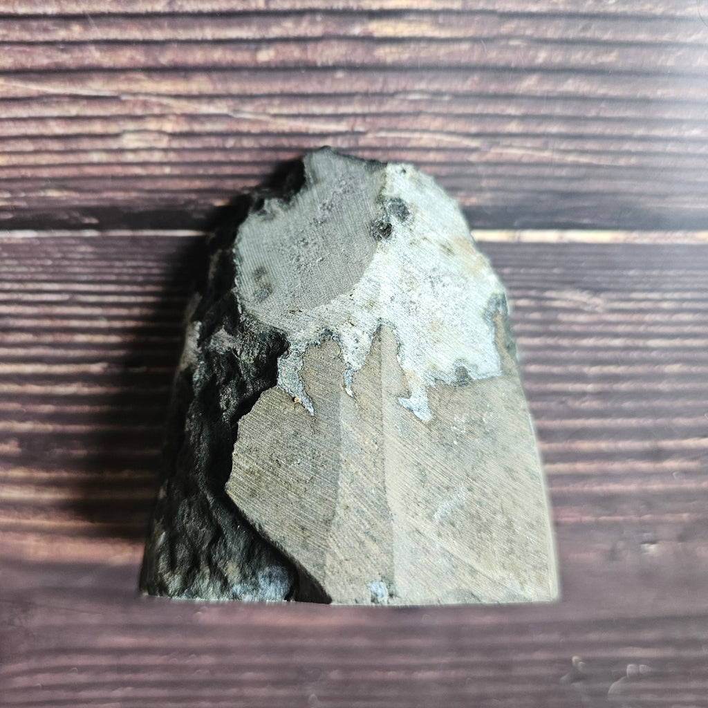 The back of an amethyst crystal, laid on a wooden surface