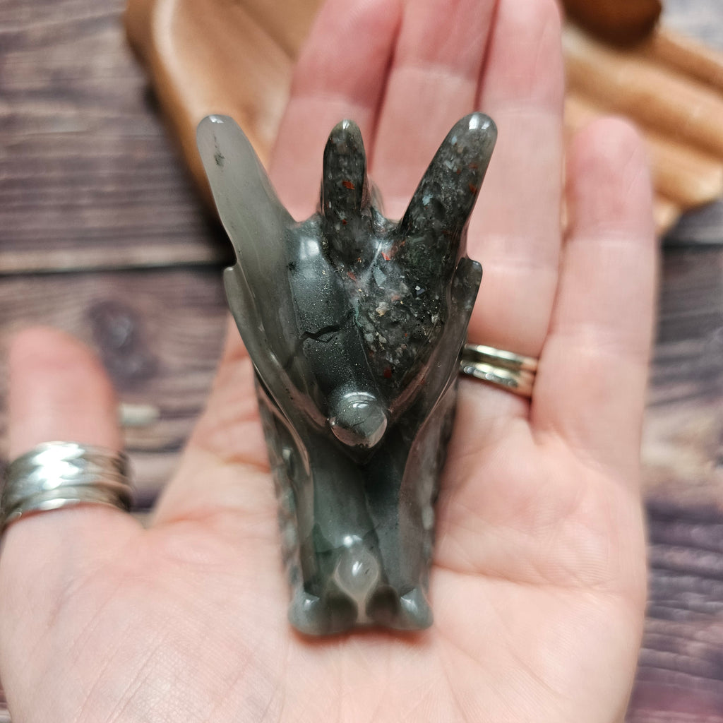 A green crystal dragon skull figurine, held in a hand