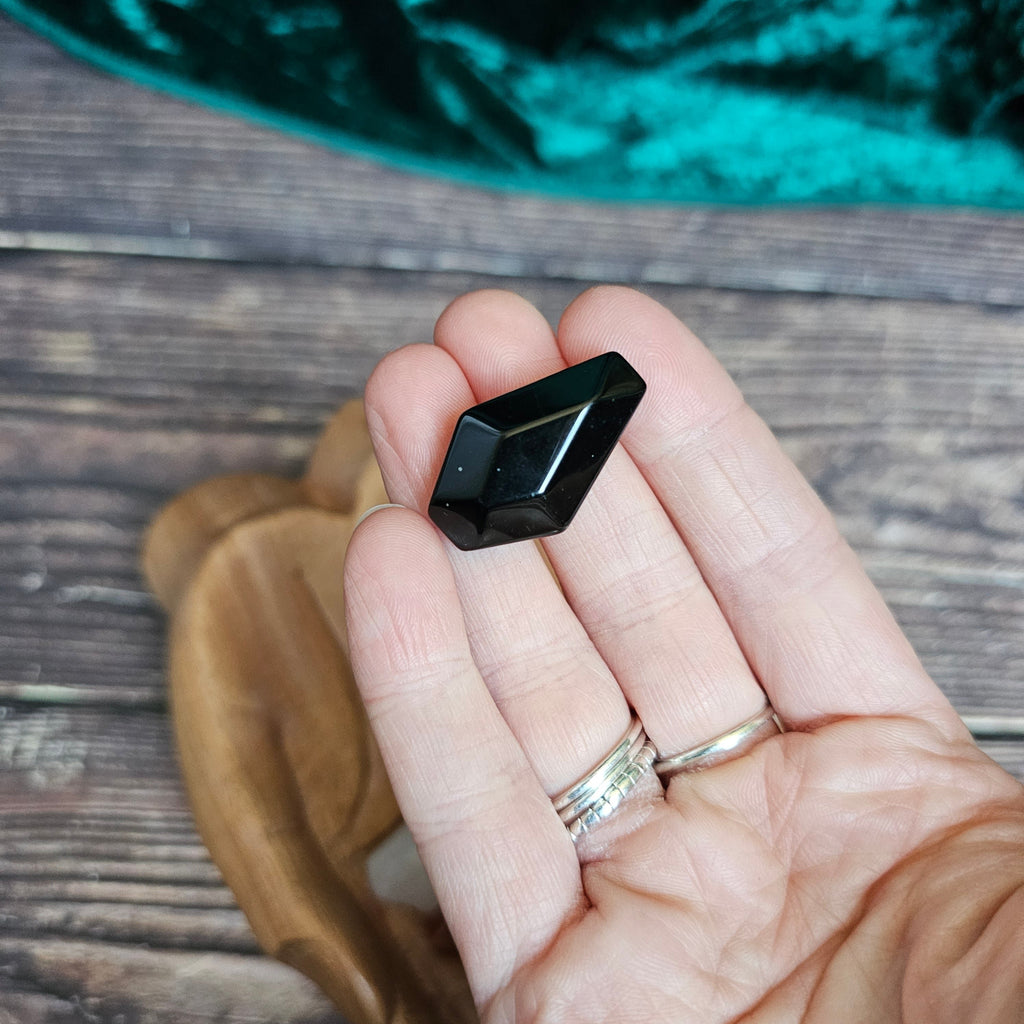 A black crystal shaped as a coffin is being held in someone's hand