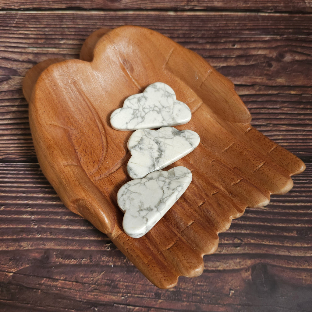 Carved Howlite crystals shaped like clouds, placed on a wooden surface.