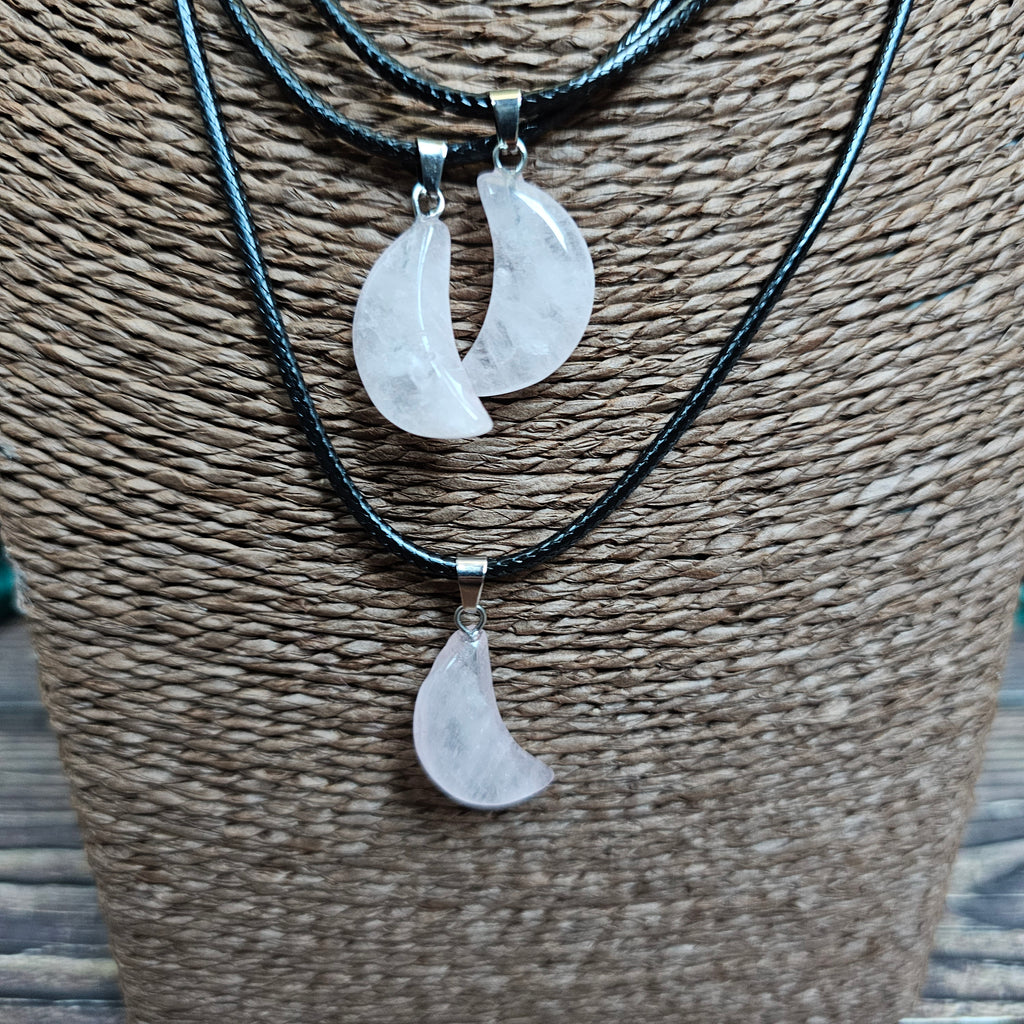 Three crescent moon shaped crystal pendants on a black cord displayed on a mannequin 